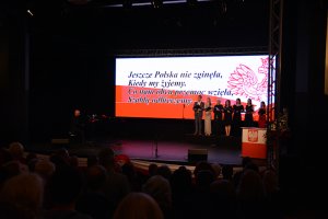 Soliści stoją na scenie MOK w Policach podczas obchodów odzyskania przez Polskę niepodległości
