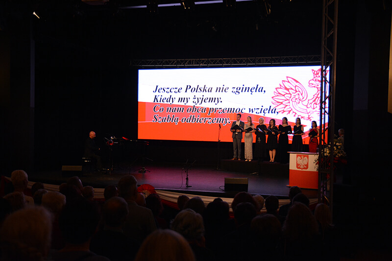 Soliści stoją na scenie MOK w Policach podczas obchodów odzyskania przez Polskę niepodległości