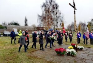 Przedstawiciele samorządu powiatowego i gminnego składają kwiaty i znicze pod brzozowym krzyżem