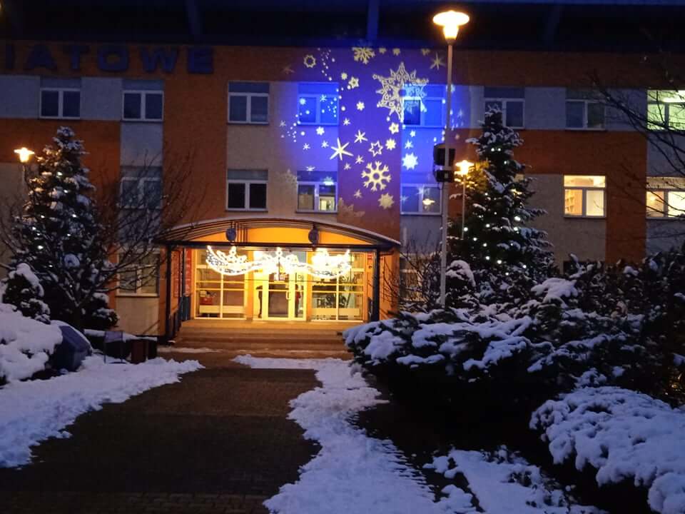 Świąteczna iluminacja na elewacji budynku Starostwa Powiatowego w Policach, sceneria w śnieżny wieczór.
