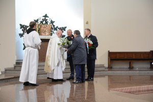 Władze samorządowe przekazują kwiaty w kościele podczas Mszy Świętej