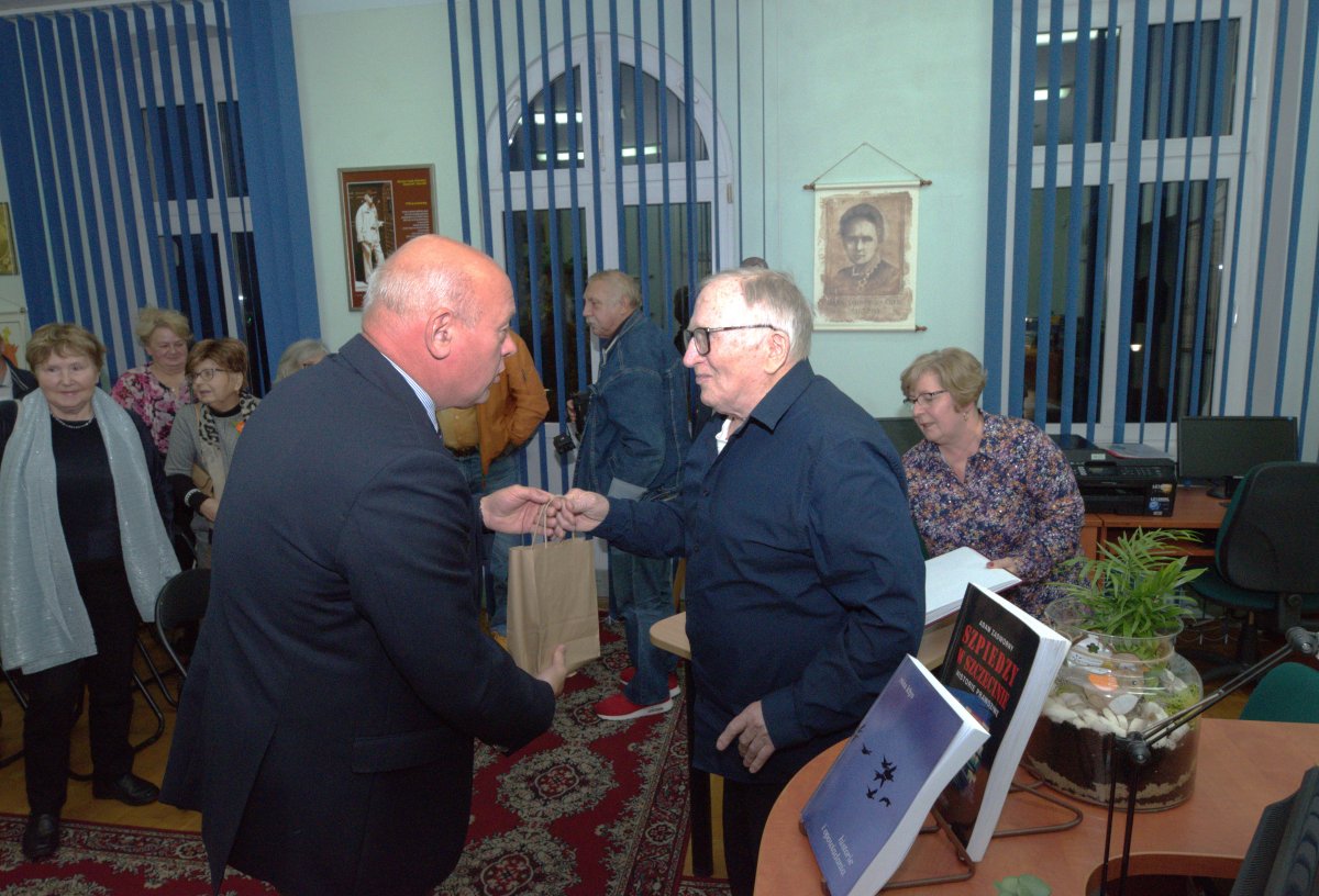 Przewodniczący Rady Powiatu w Policach wręcza upominek malarzowi