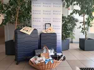 Walizki i kosz upominkowy, w tle element reklamowy