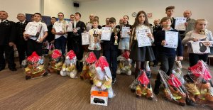 Najmłodsi uczestnicy konkursu pożarniczego z dyplomami i nagrodami pozują do zdjęcia grupowego.