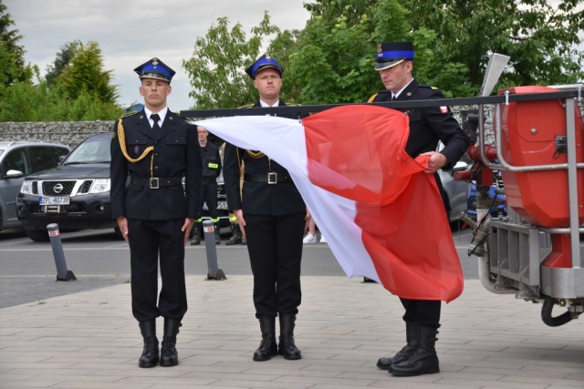 Strażacy wieszają flagę Polski.