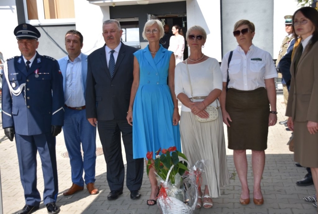 Przedstawiciele władz samorządowych stoją na dziedzińcu Komendy Powiatowej w Policach wraz z upominkiem.