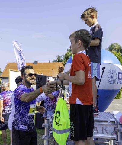 Starosta Policki podaje nagrodę dziecku na podium