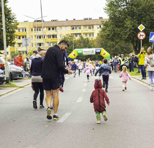 Rodzic stoi obok swojego dziecka, które bierze udział w biegu najmłodszych uczestników