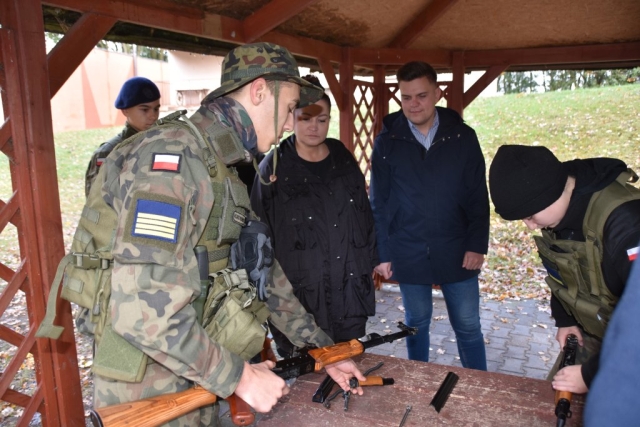 Wicestarosta policki obserwuje broń, którą pokazuje ubrany mundurowy