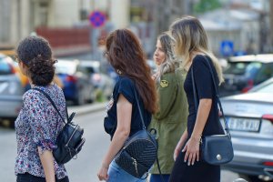 Kobiety idące ulicą z plecakami i torebką